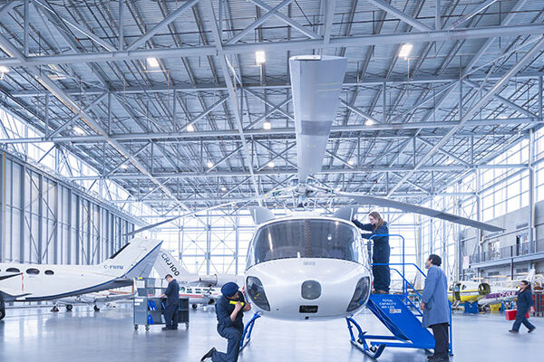 Technicians working on a helicopter inside a hangar